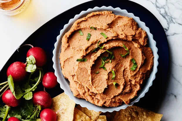 Creamy bean dip served in a bowl with radishes.
