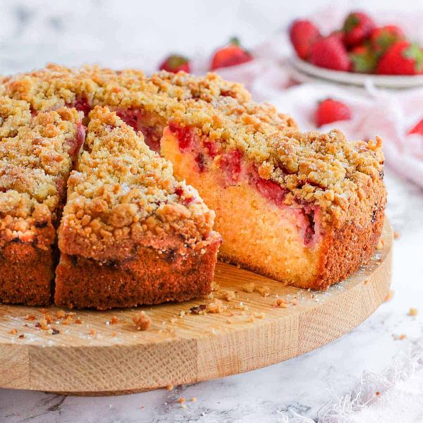 Cake with strawberries and crumb cut on a cutting board.