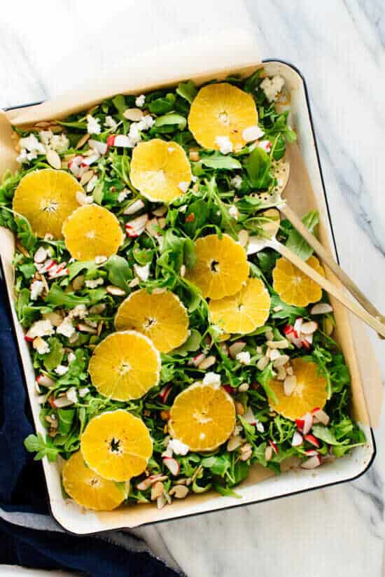 Rucola-Salat mit frischen Orangen und Radieschen in einer Servierschüssel.