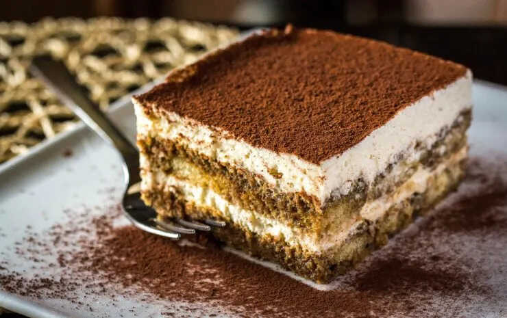 A piece of traditional tiramisu with mascarpone on a plate with a fork.