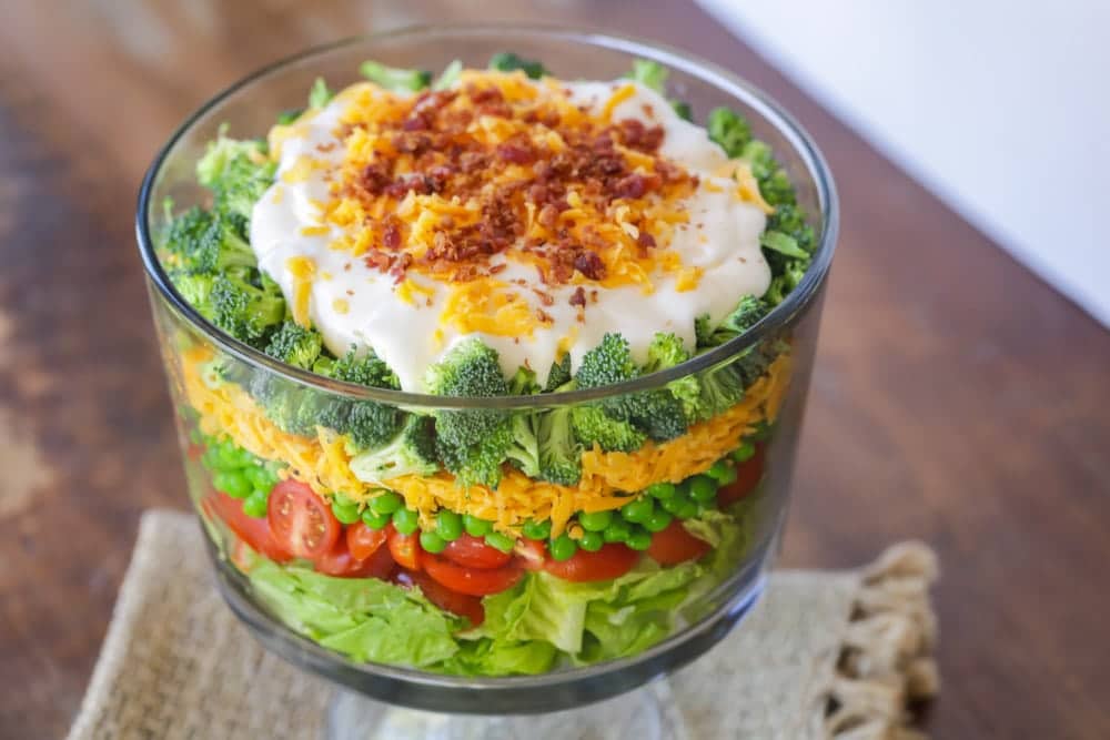 Vegetable salad with cheese and bacon served in a glass bowl.