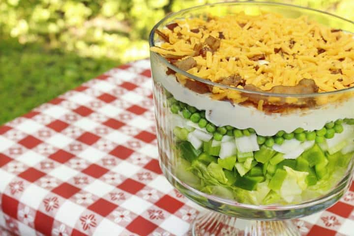 Vegetable salad with dressing sprinkled with cheese and bacon, served in a glass bowl.