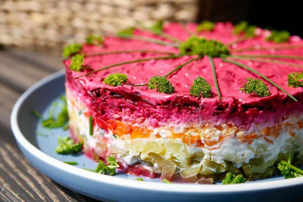 Warm vegetable salad with beetroot garnished with fresh herbs, served on a plate.