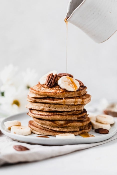Banana-oat pancakes decorated with banana slices and pecans.
