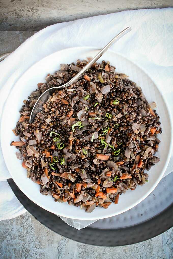 Lentils with vegetables served on a plate with a spoon.