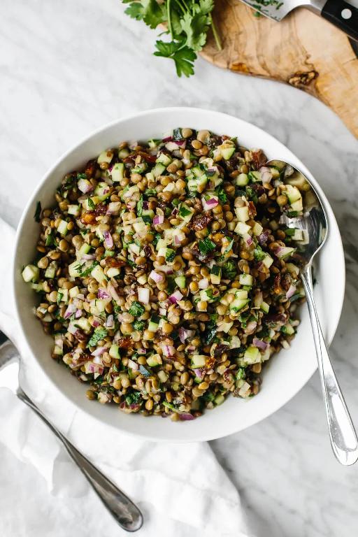 Lentils with pickles and dressing served on a plate with a spoon.