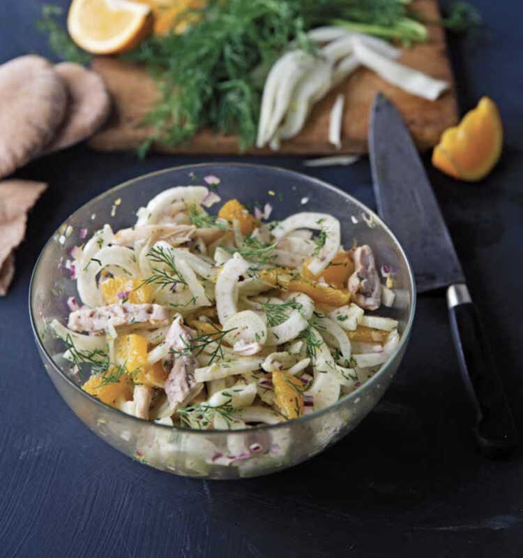 Fennel and chicken salad served in a glass bowl with a knife next to it.