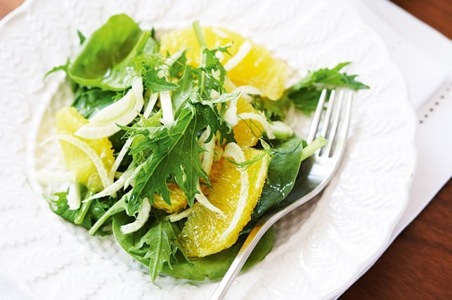 Leaf salad with oranges and fennel on a plate with a fork.