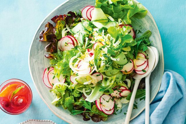 Salad with fennel and radishes served in a bowl with spoons.