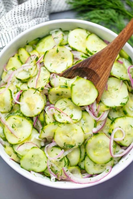 A mixture of cucumber slices, red onion and dill in a simple salad.