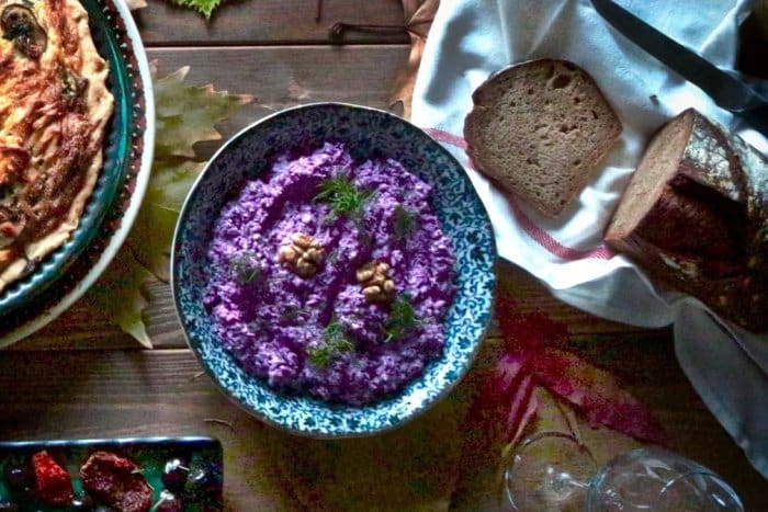 A bowl with a spread of various ingredients including red cabbage and nuts.