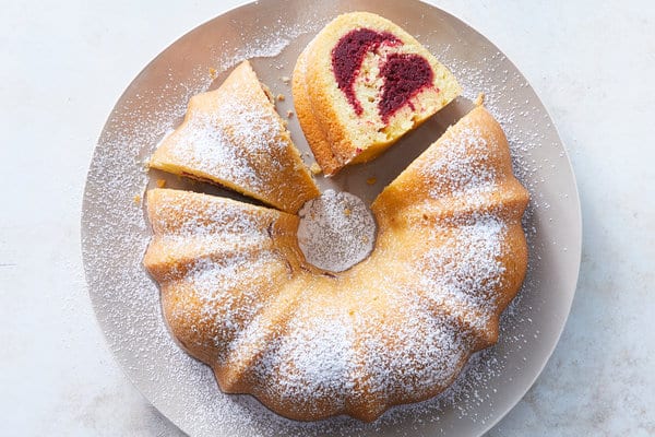 Olive oil cake with beetroot served on a plate and sprinkled with powdered sugar.