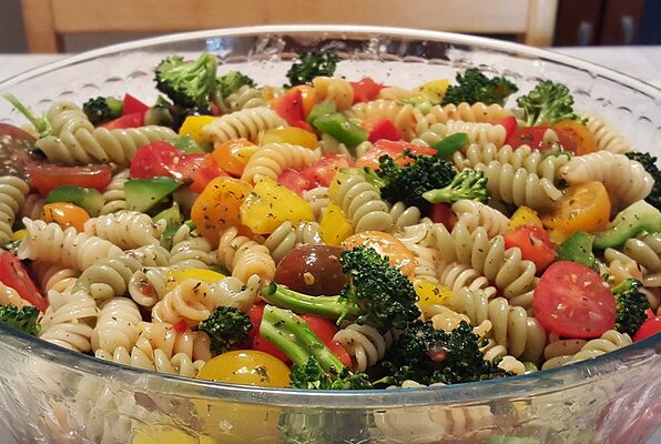 Pasta salad with tomatoes, olives and peppers of three colors.