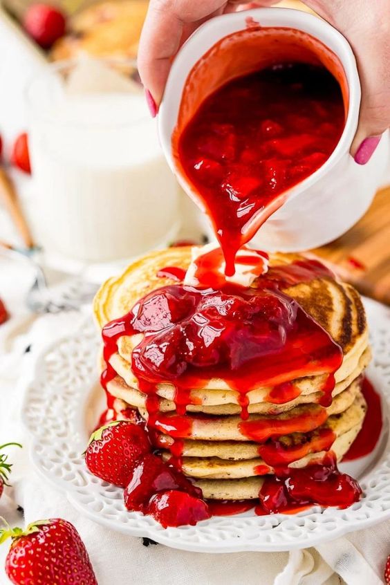 Tall pancake tower with strawberry topping.