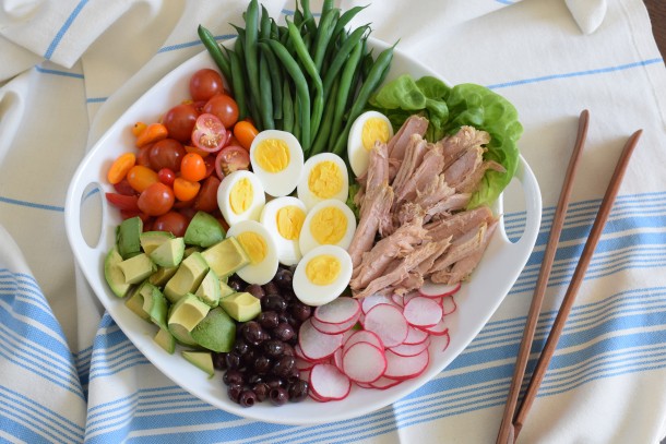 Salát s vajíčkem, avokádem a zeleninou servírovaný na talíři s vedle položenými hůlkami.