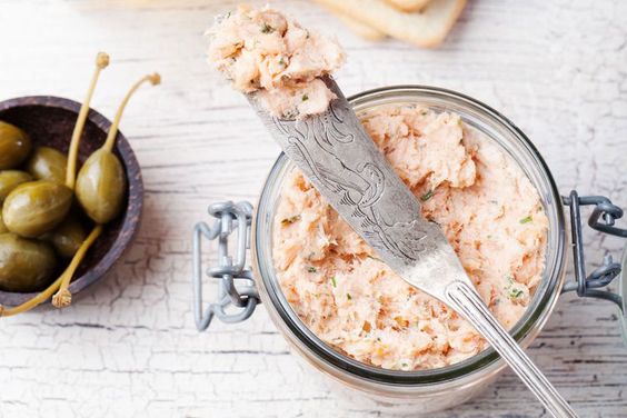 Cream spread on a knife and in a cup with capers.