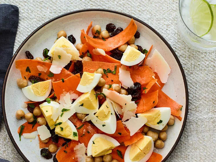 Carrot, chickpea, raisin, parmesan and egg salad served on a plate.