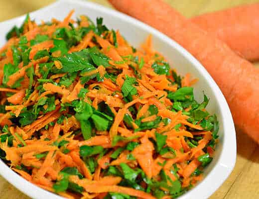 Salad with carrots, fresh parsley, spring onions and mango juice and fresh horseradish dressing served in a bowl.