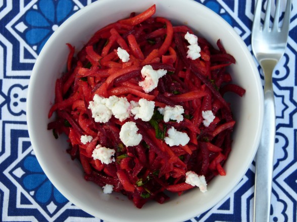Carrot, beetroot, feta and dressing salad served on a plate with a fork next to it.