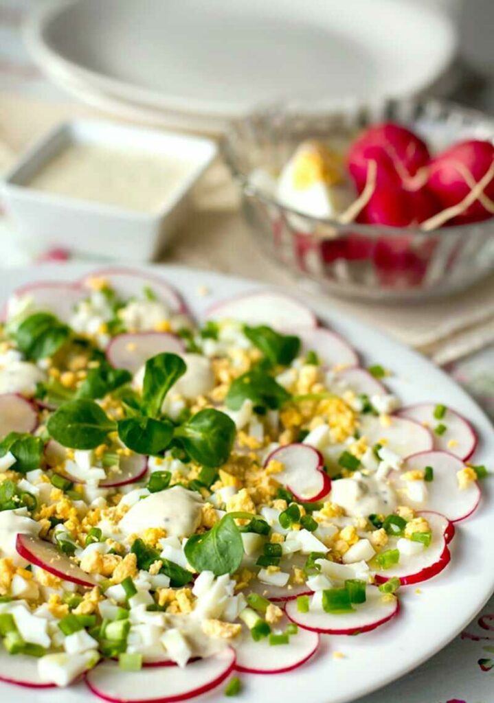 Radish salad with hard-boiled egg and creamy dressing served on a plate.