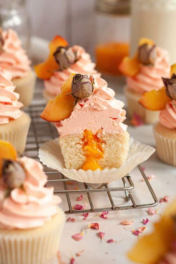 Peach-raspberry cupcake filled with peach filling and decorated with raspberry cream.