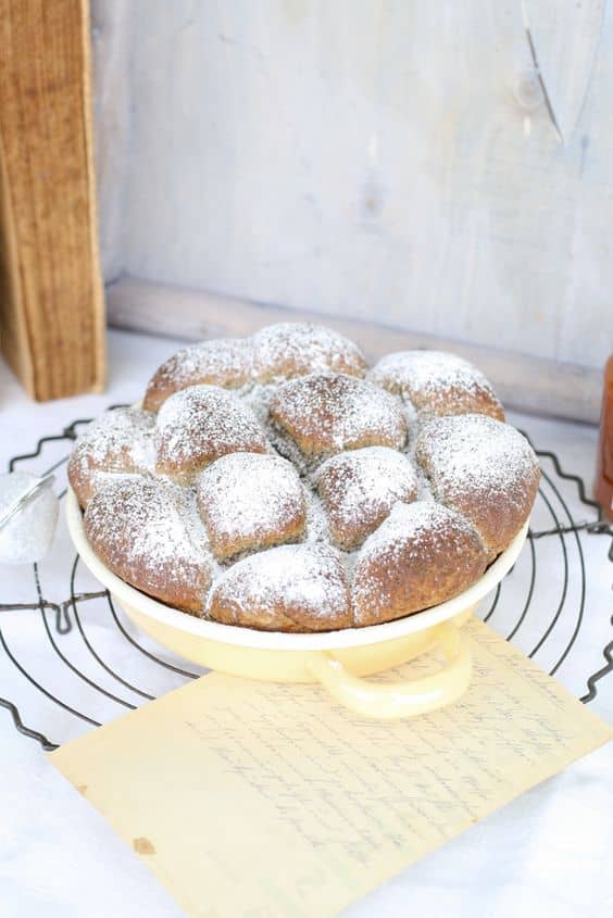 Buns filled with cottage cheese and sprinkled with powdered sugar in a baking pan.