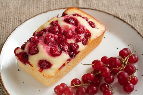 Yoghurt and currant bread on a plate with fresh currants next to it.