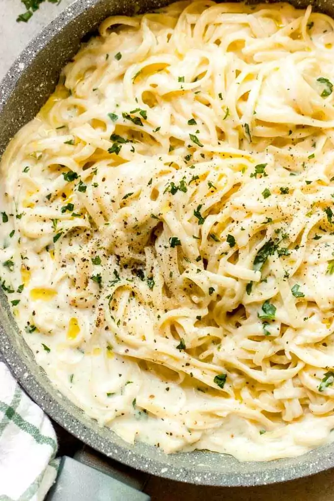 Omáčka z česneku se špagetami servírovaná v hlubokém talíři a posypaná čerstvými bylinkami.