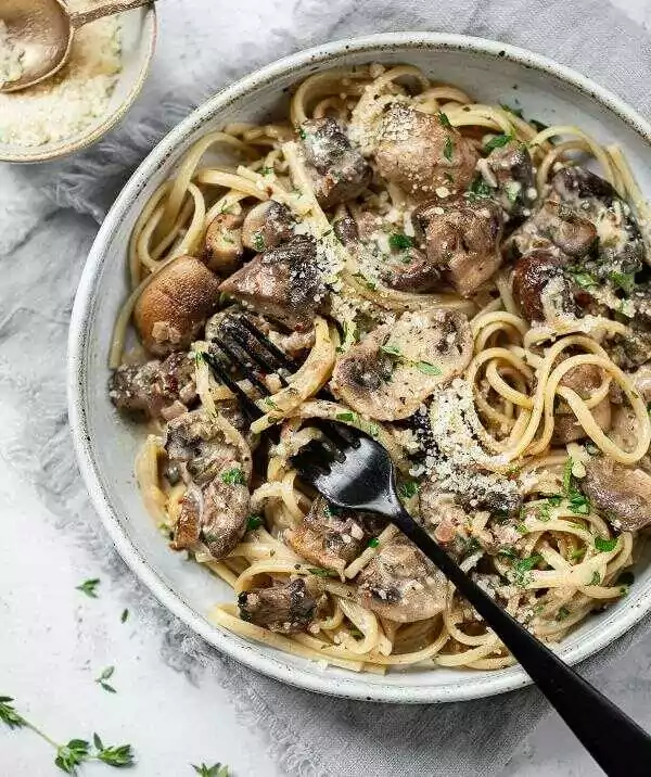 Spaghetti mit Pilzsauce, serviert in einem tiefen Teller mit einer Gabel.