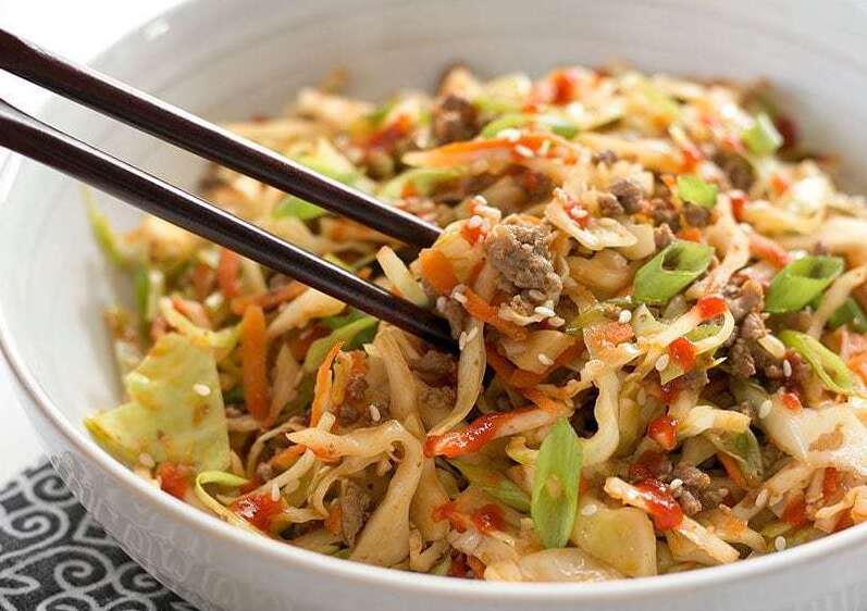 Asian-style stir-fried meat with vegetables served with a bowl with chopsticks.