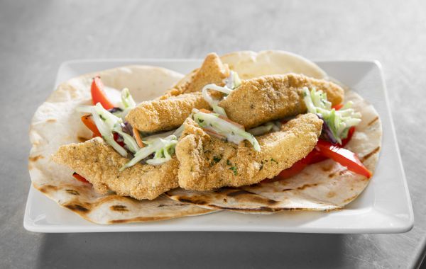 Fried fish strips served on tortillas with fresh vegetables and coleslaw.