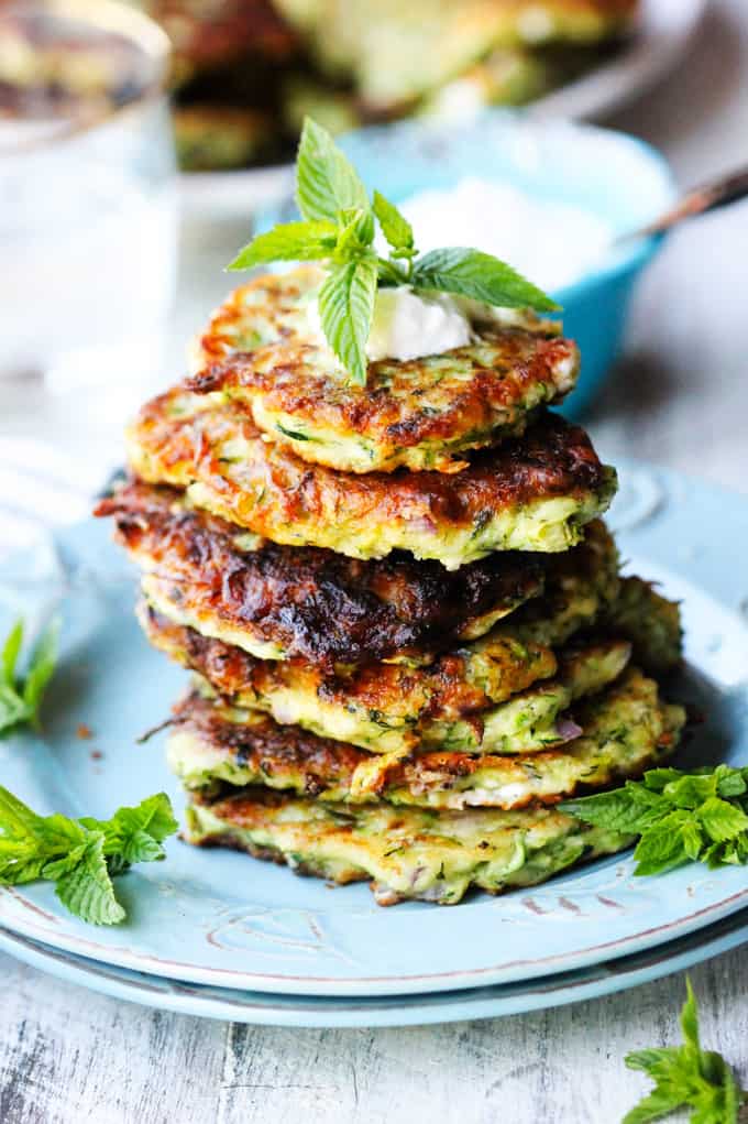 Zucchini meatballs with feta and herbs stacked on top of each other on a plate.