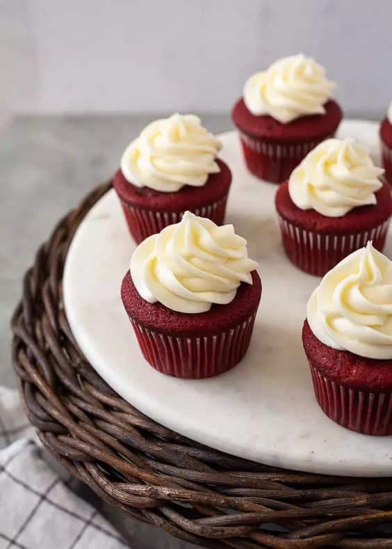 Red velvet cupcake with vanilla cream and red sprinkles.