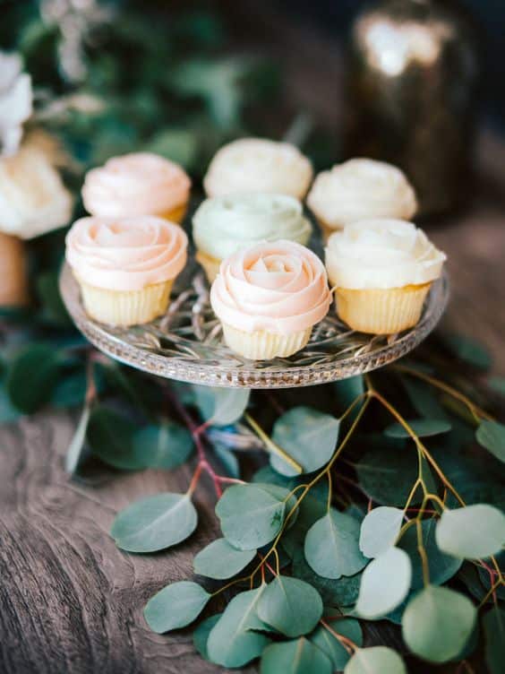 Hochzeits-Cupcakes mit Sahne dekoriert und auf einem Glasuntersetzer ausgestellt.