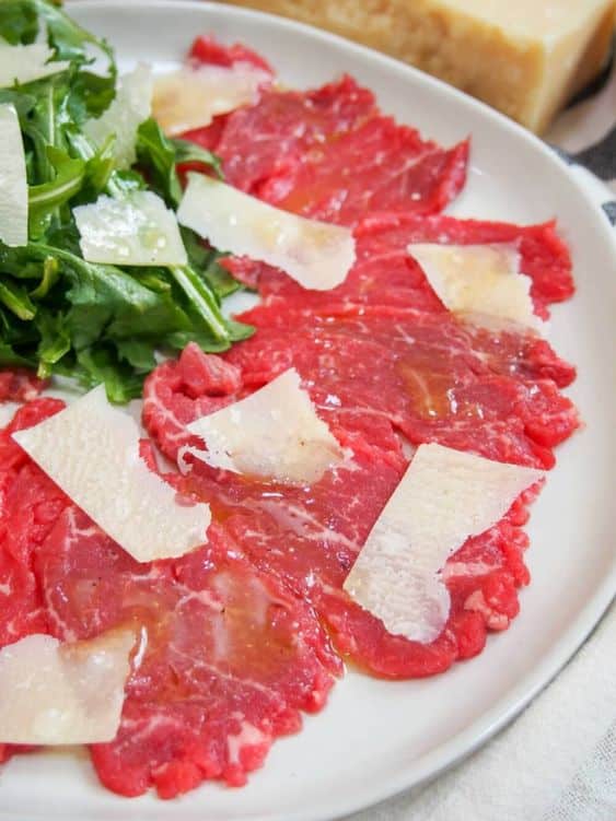 Sliced veal with oil and bitter rocket.