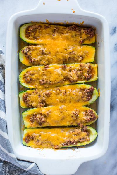 Zucchini stuffed with meat mixture and baked with cheese, served in a baking dish.