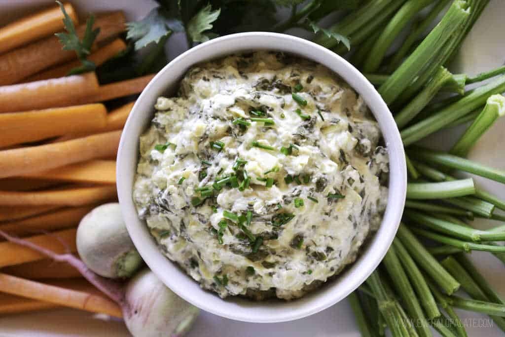Vegetable and cheese dip served in a bowl and topped with fresh vegetables.
