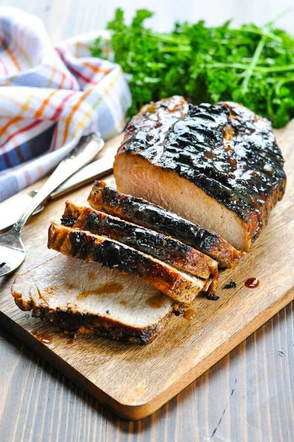 Roast pork with honey glaze served on a wooden board.