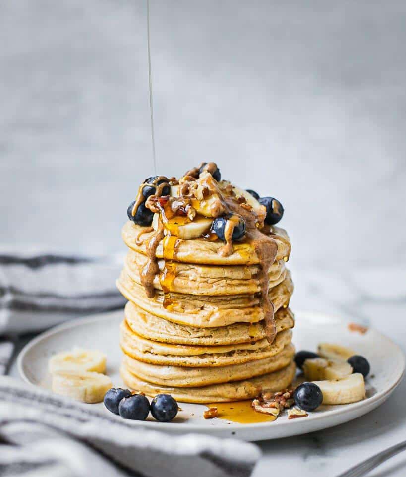 Pancakes with buttermilk stacked on a plate, decorated with fresh fruit and toppings.