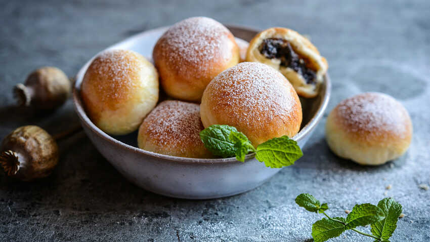 Buns filled with poppy seeds served in a bowl and sprinkled with powdered sugar.