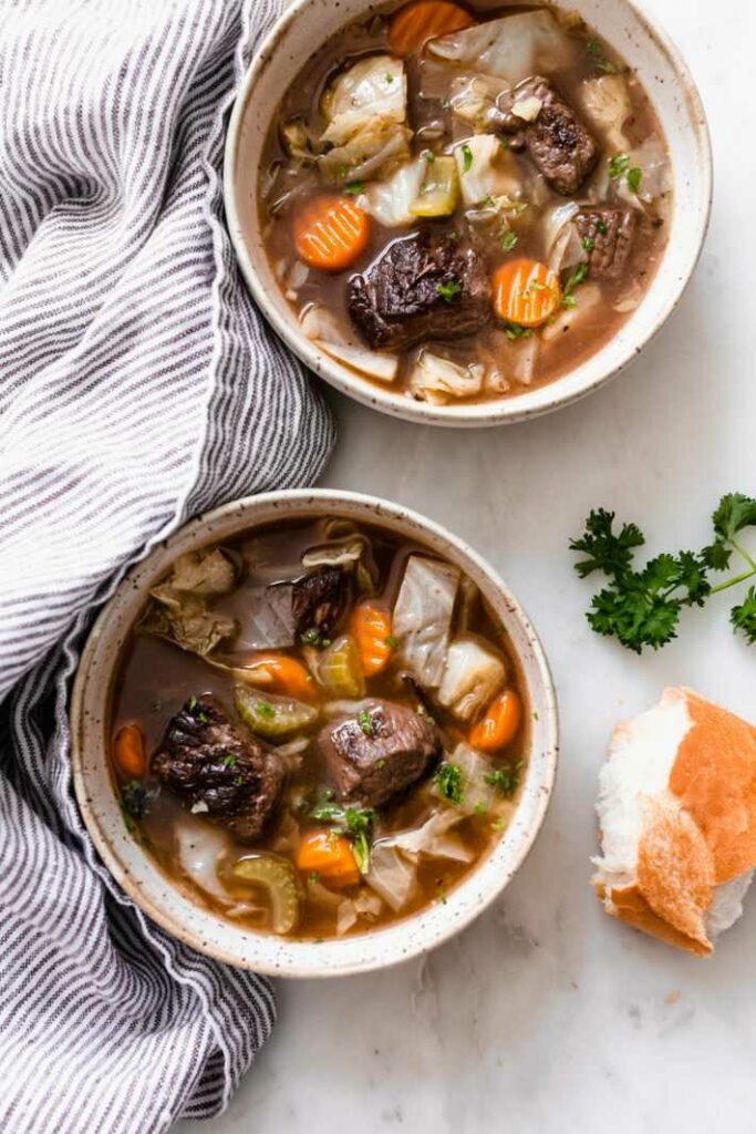 Vegetable soup with beef served in two deep plates.