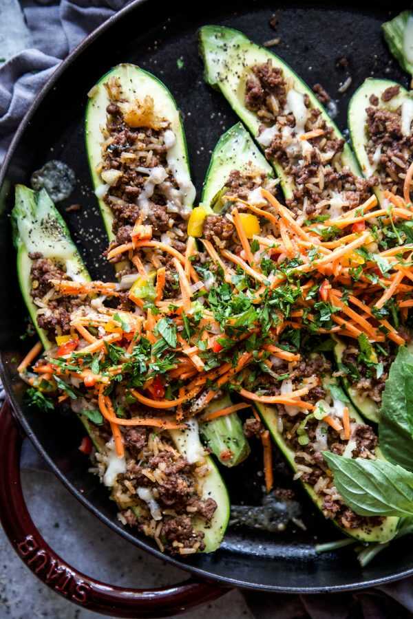 Zucchini baked with a mixture of Thai-style ground beef and coconut rice, garnished with carrots, peppers and fresh herbs.