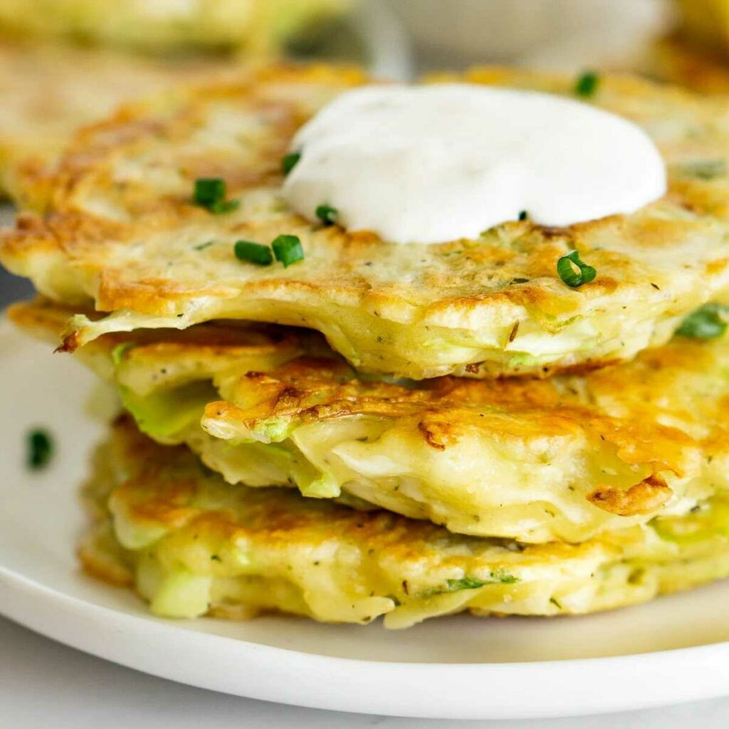 Cabbage pancakes with creamy garlic dip served on a plate.