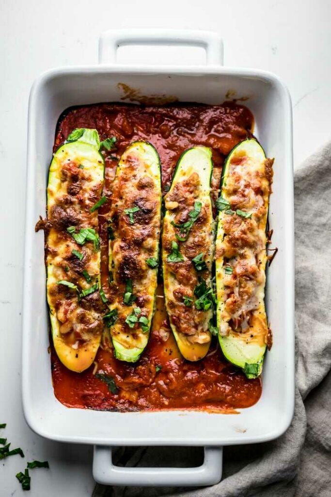 Zucchini stuffed with a vegetarian mixture, baked with cheese and served in a baking dish with tomato sauce.