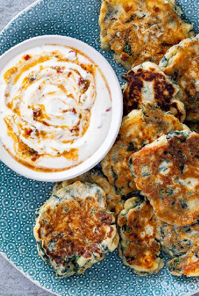 Cabbage and feta pancakes served with a bowl of dip.