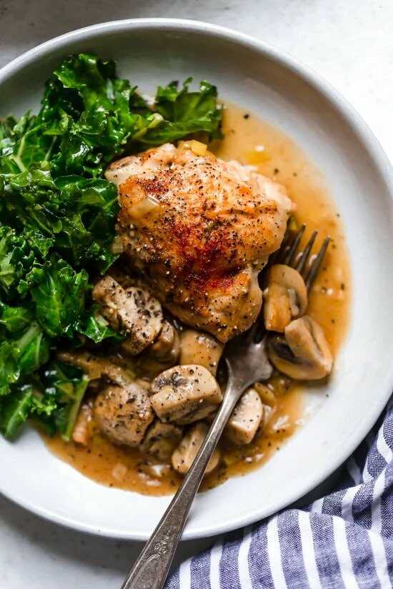 Chicken with mushrooms and green vegetables served on a plate with a fork.