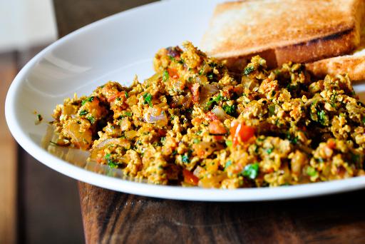 Vaječina na indický způsob servírovaná na talíři s opečeným chlebem.