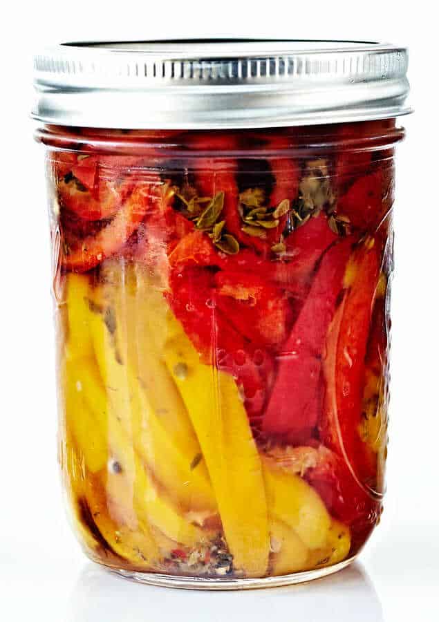 Žluté a červené papriky naložené v zavařovací sklenici.