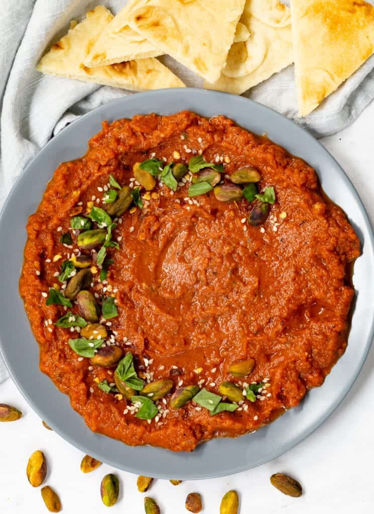 Paprika dip served in a bowl, sprinkled with herbs and nuts.