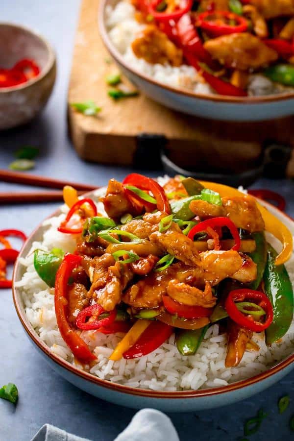 Kuřecí maso, zelenina a rýže na asijský způsob, to vše servírováno v hlubokém talíři.